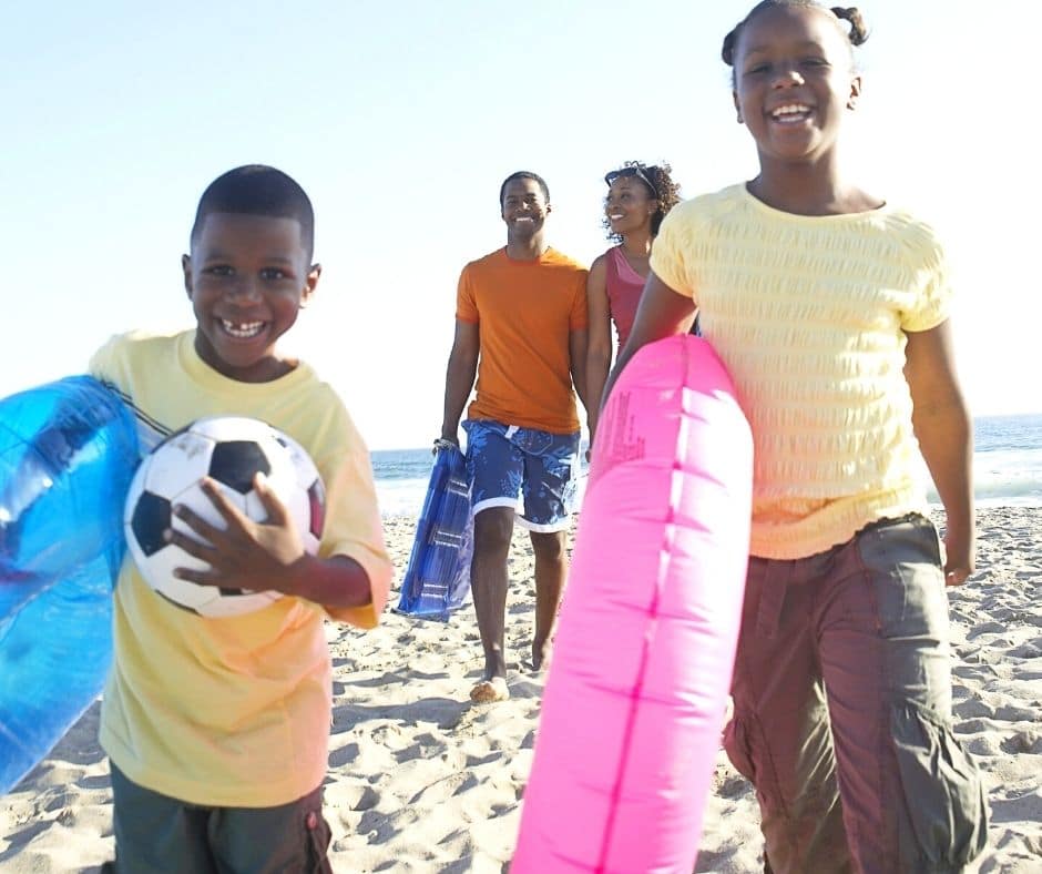 Family on the beach holding a soccer ball and floating tubes