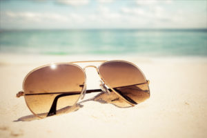 Sunglasses on sandy beach in summer - vintage color styles