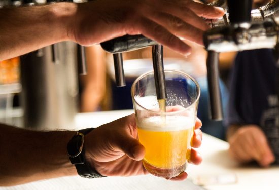 beer poured into glass at bar