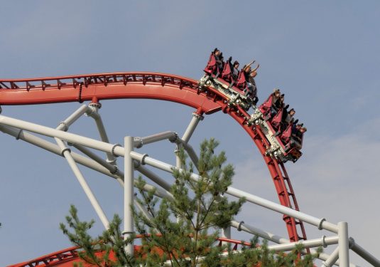 Red and white roller coaster with people having their hands up Red and white roller coaster with people having their hands up