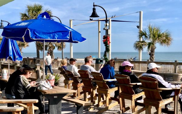 Myrtle Beach, South Carolina, US-December 26, 2019: Tourists enjoying the oceanfront restaurants and attractions on the beach boardwalk right after Christmas Day, in a sunny winter day.